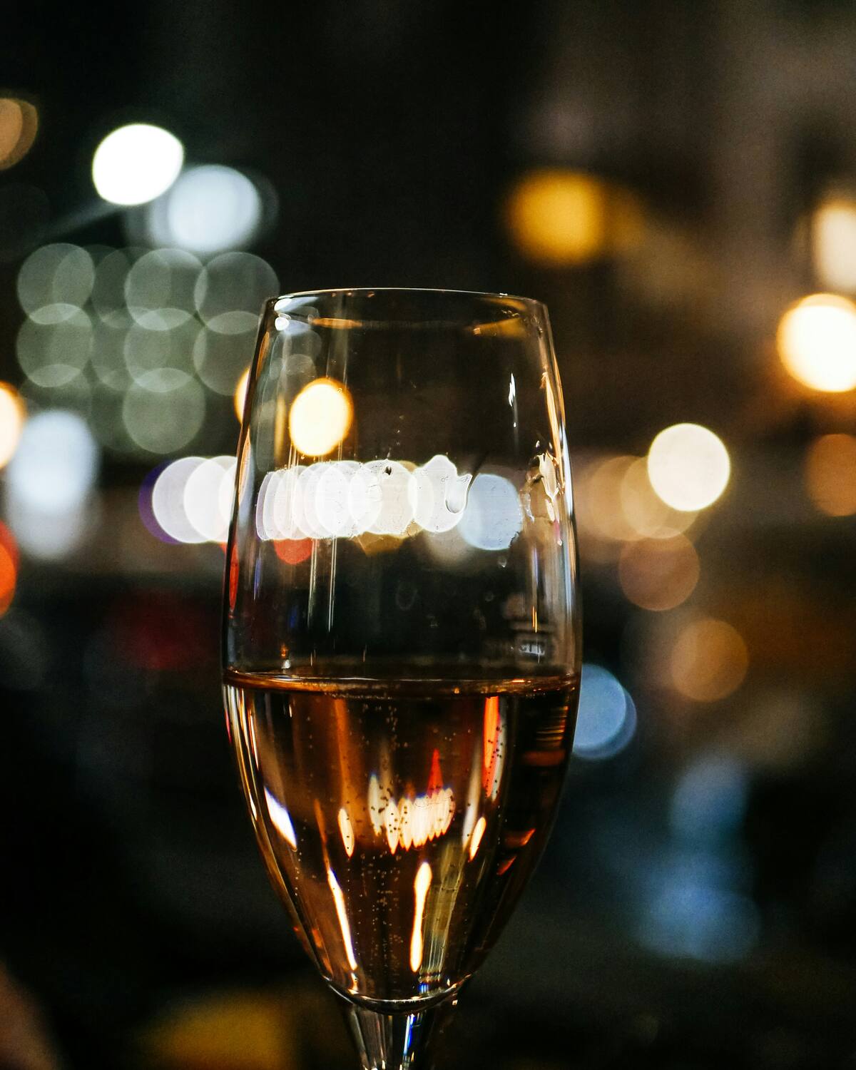 Ein Glas Champagner vor den unscharfen Lichtern der Stadt am Abend.